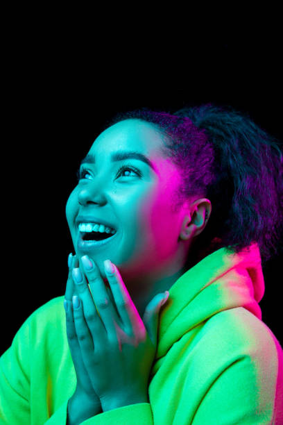istock African-american woman's portrait isolated on dark studio background in multicolored neon light 1297171688