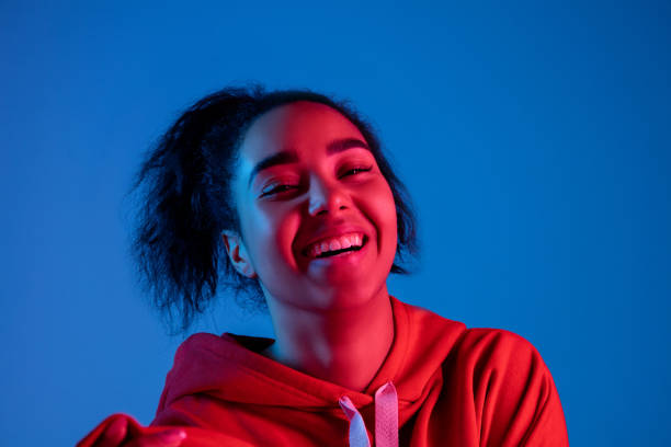 istock African-american woman's portrait isolated on blue studio background in multicolored neon light 1297171887