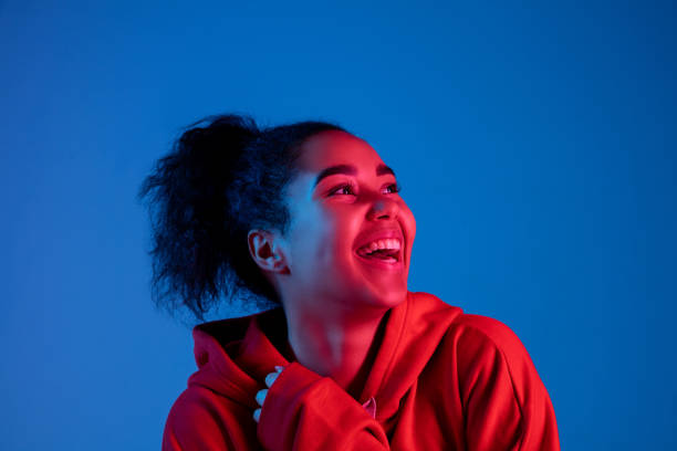 African-american woman's portrait isolated on blue studio background in multicolored neon light