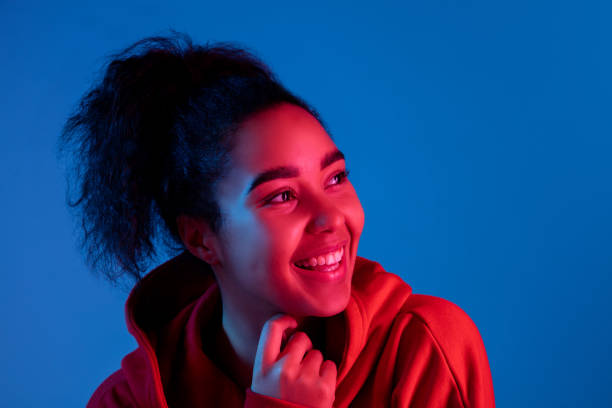 istock African-american woman's portrait isolated on blue studio background in multicolored neon light 1297171890