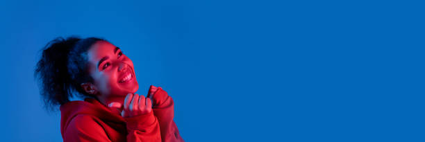 African-american woman's portrait isolated on blue studio background in multicolored neon light