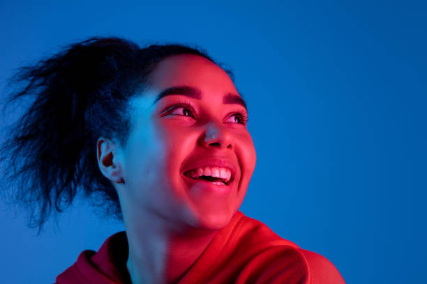 istock African-american woman's portrait isolated on blue studio background in multicolored neon light 1297171895