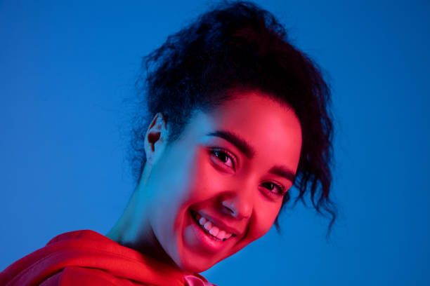 istock African-american woman's portrait isolated on blue studio background in multicolored neon light 1297171897