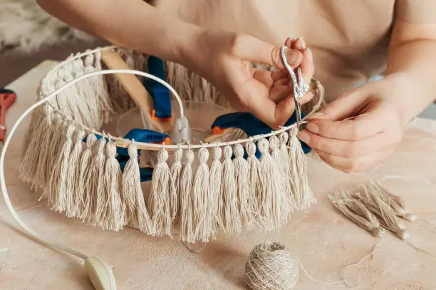 woman makes a lamp shade with handmade tassels.