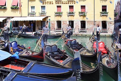 Venice. Italy - May 1, 2007: Gondoliers with moored gondolas in front of the popular Hotel Cavalletto.