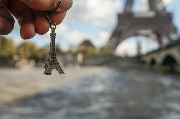 Hand with a small eiffel tower souvenir in a hand over real Eiffel tower