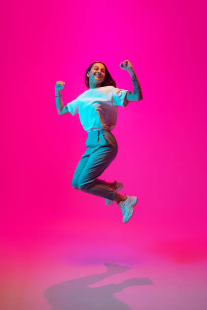 istock Caucasian beautiful woman's portrait isolated on pink studio background in multicolored neon light 1297174918