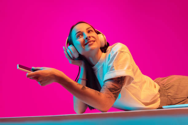 Caucasian beautiful woman's portrait isolated on pink studio background in multicolored neon light