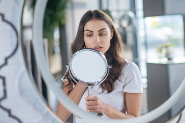 istock Woman checking her skin while looking at the mirror 1297175417