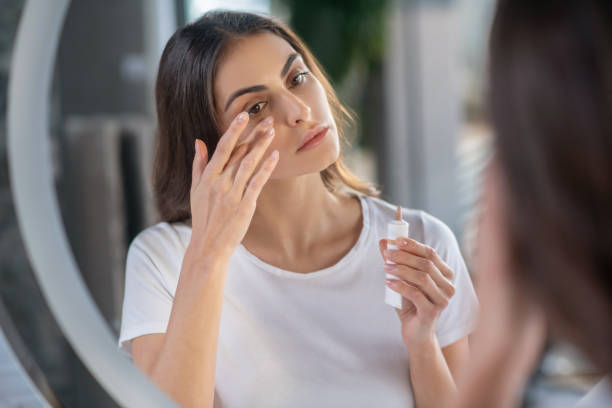 Woman appying a concealer to her skin Beauty routine. A woman appying a concealer to her skin concealer stock pictures, royalty-free photos & images