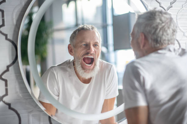 istock Man making funny faces near the mirror 1297175517
