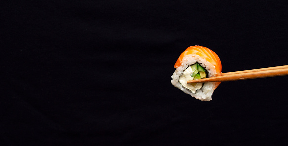 Banner with one sushi roll on black background with large copy space