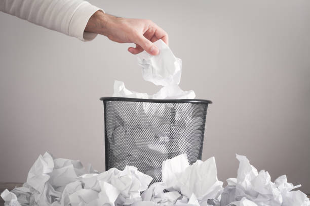 istock Man throwing crumpled paper into trash can. 1297176458