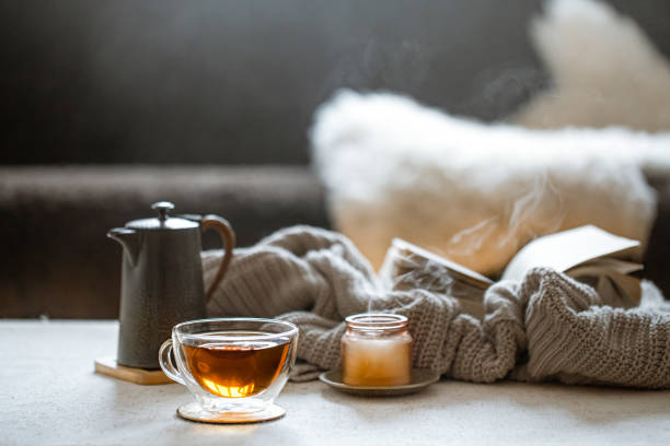 istock Cozy home composition with cup of tea, kettle and candle on blurred background ccopy space. 1297180244