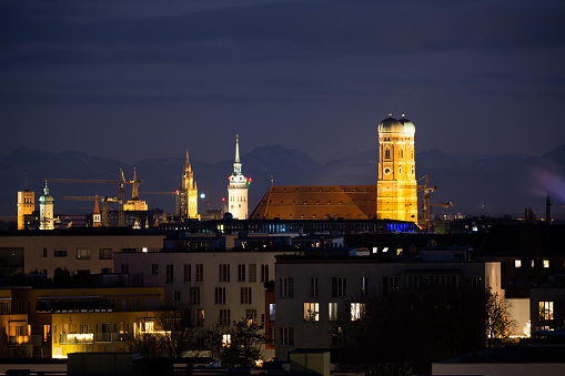 A look of the Munich Cathedral towers from far away showing the city skyline and the alps