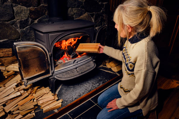 Wood burning stove Woman putting a well dried log into a glowing wood burning stove. wood burning stove stock pictures, royalty-free photos & images