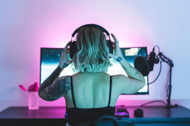 weibliche spielerin setzt ihre kopfhörer auf - computerspiel konsole fotos stock-fotos und bilder