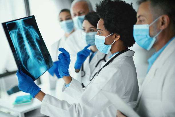 equipo de médicos analizando una imagen de rayos x de un paciente covid-19. - x ray image radiologist examining using voice fotografías e imágenes de stock