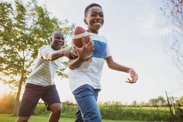 vater und sohn spielen hinterhoffußball - child american football football sport stock-fotos und bilder