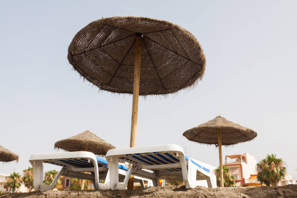 istock Wicker sun umbrellas with blue and orange hammocks on empty beach at dawn. 1297187339