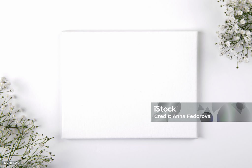 Canvas mockup with smal white flowers on a white background Canvas mockup with smal white flowers on a white background. Design element for Valentines Day and Mother Day congratulation, thank you, greeting or invitation card, art work RSVP Stock Photo