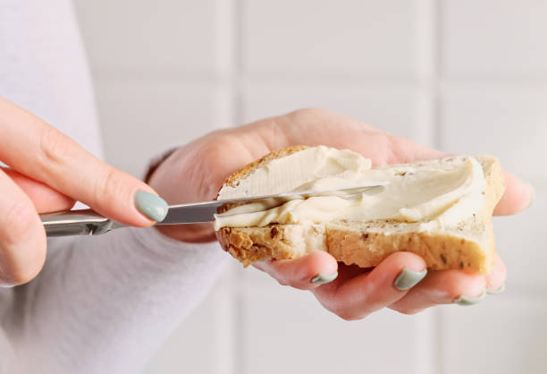 mani femminili che fanno un panino. donna che prepara la colazione, mette il formaggio su toast - butter margarine fat bread foto e immagini stock