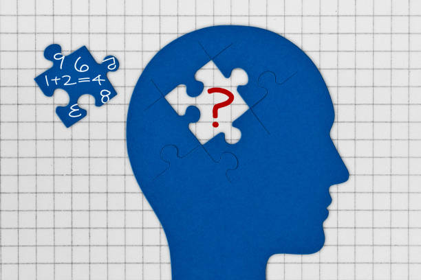Head profile with brain made of jigsaw puzzle pieces on squared paper sheet - Concept of dyscalculia and problems with numbers