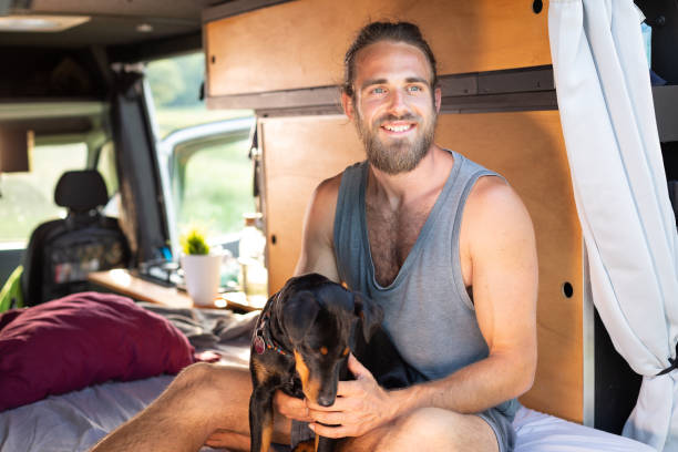 istock Smiling man and his dog inside a camper van 1297189776