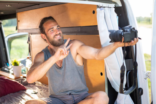 istock Young man in a camper van pointing a camera at himself 1297189788