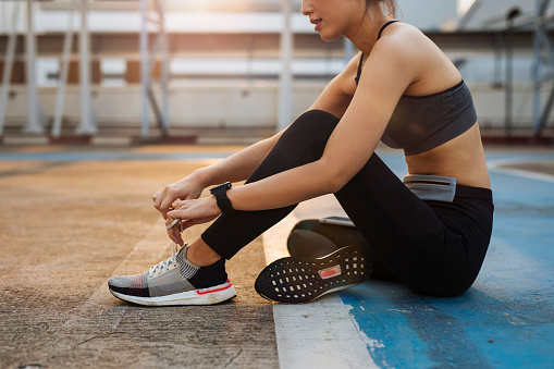 Cropped image of a woman runner tying laces on sneakers