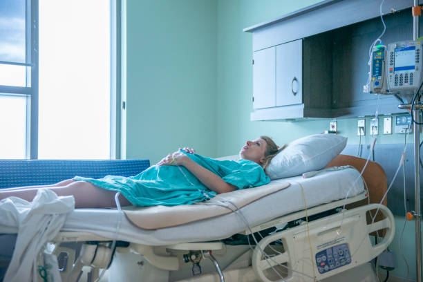 Pregnant woman at delivery room A pregnant Caucasian woman is on the hospital bed at the delivery room. She is trying to manage her pain from her contractions. She is about to give birth to her child. dilation stock pictures, royalty-free photos & images