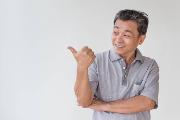 istock old, middle aged, senior asian man pointing thumb up finger gesture 1297193410