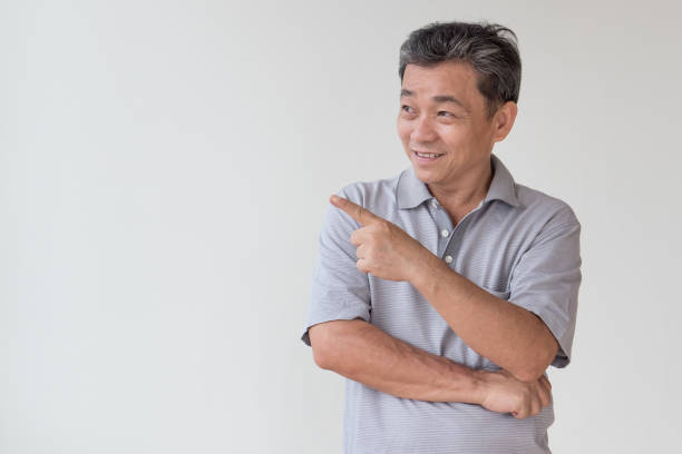 istock old, middle aged, senior asian man looking and pointing finger away gesture 1297193472