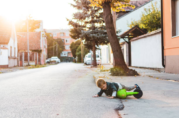 Boy fall down while riding motorcycle around the neighborhood Boy fall down while riding motorcycle around the neighborhood. motorcycle 4 wheels stock pictures, royalty-free photos & images