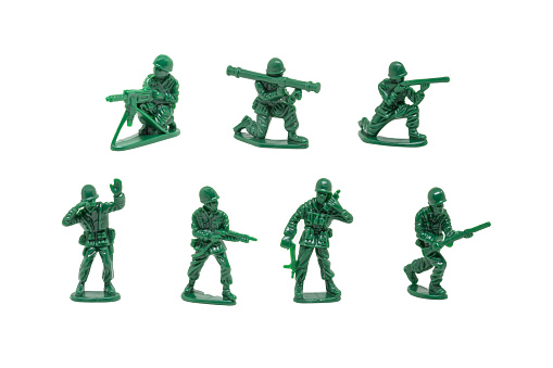 Square composition photography of concept of leadership, with little green soldier toy aiming the way forward, with arm raised, concept of teamwork in business. Macro picture shot, taken isolated on white background in studio. The dominant color is green khaki.