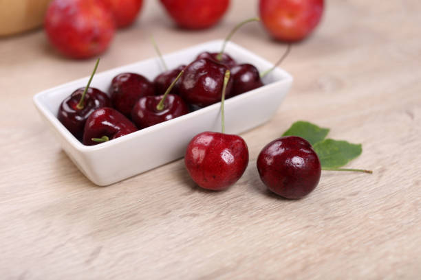 istock Fresh cherry in white dish on wooden background 1297196895