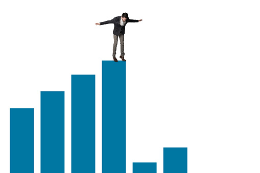 Shot of a businessman about to jump from the edge of a graph against a white background