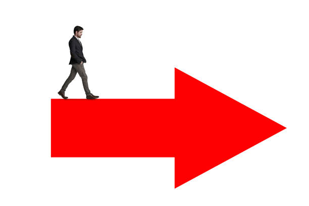 Shot of a businessman waking across a red arrow against a white background