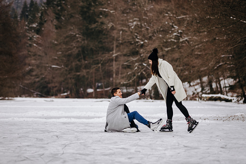 Couple ice skating on a frozen lake.