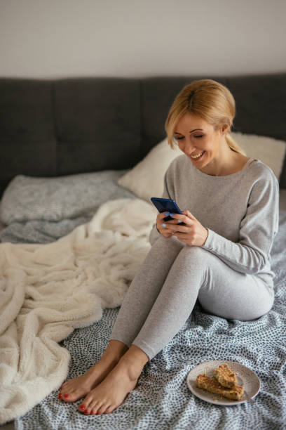 istock Young women sitting on bed and using mobile phone 1297197619