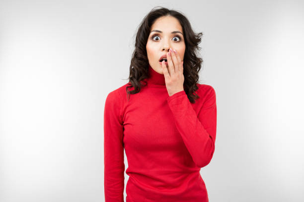 istock surprised brunette girl in a red sweater on a gray studio background with copy space 1297198459