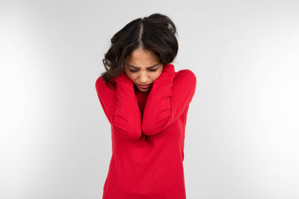 istock Uncertain brunette girl in a red sweater trying to hide on a white studio background 1297198467