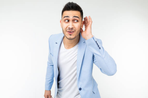 istock charming guy in a blue jacket suspiciously listens on a white background with copy space 1297198713