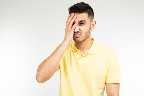 istock Caucasian guy in a yellow T-shirt feels a headache on a white studio background 1297199434