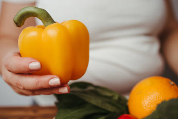 istock Fat woman snacking with fruits and vegetables 1297199776