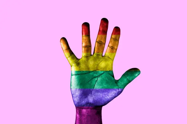 Photo of Open palm with the colors of the rainbow of gay pride. LGBT equal rights movement and gender equality concept.