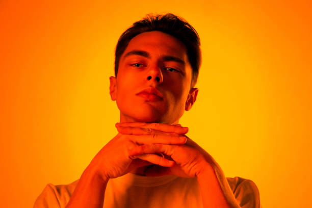 Handsome caucasian man's portrait isolated on orange studio background in neon light, monochrome