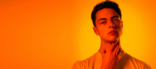 istock Handsome caucasian man's portrait isolated on orange studio background in neon light, monochrome 1297201868