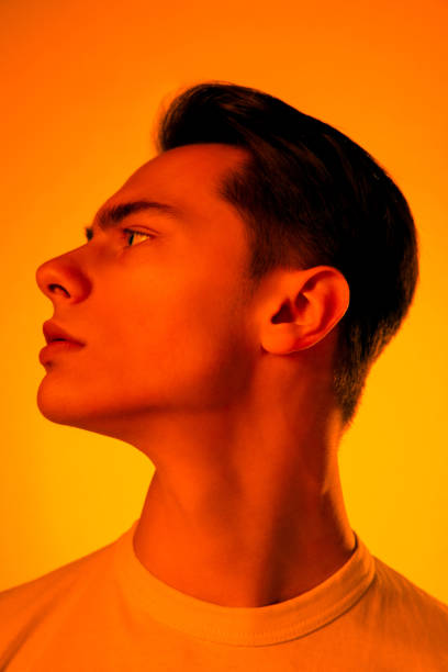 istock Handsome caucasian man's portrait isolated on orange studio background in neon light, monochrome 1297201898