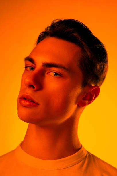 istock Handsome caucasian man's portrait isolated on orange studio background in neon light, monochrome 1297201902